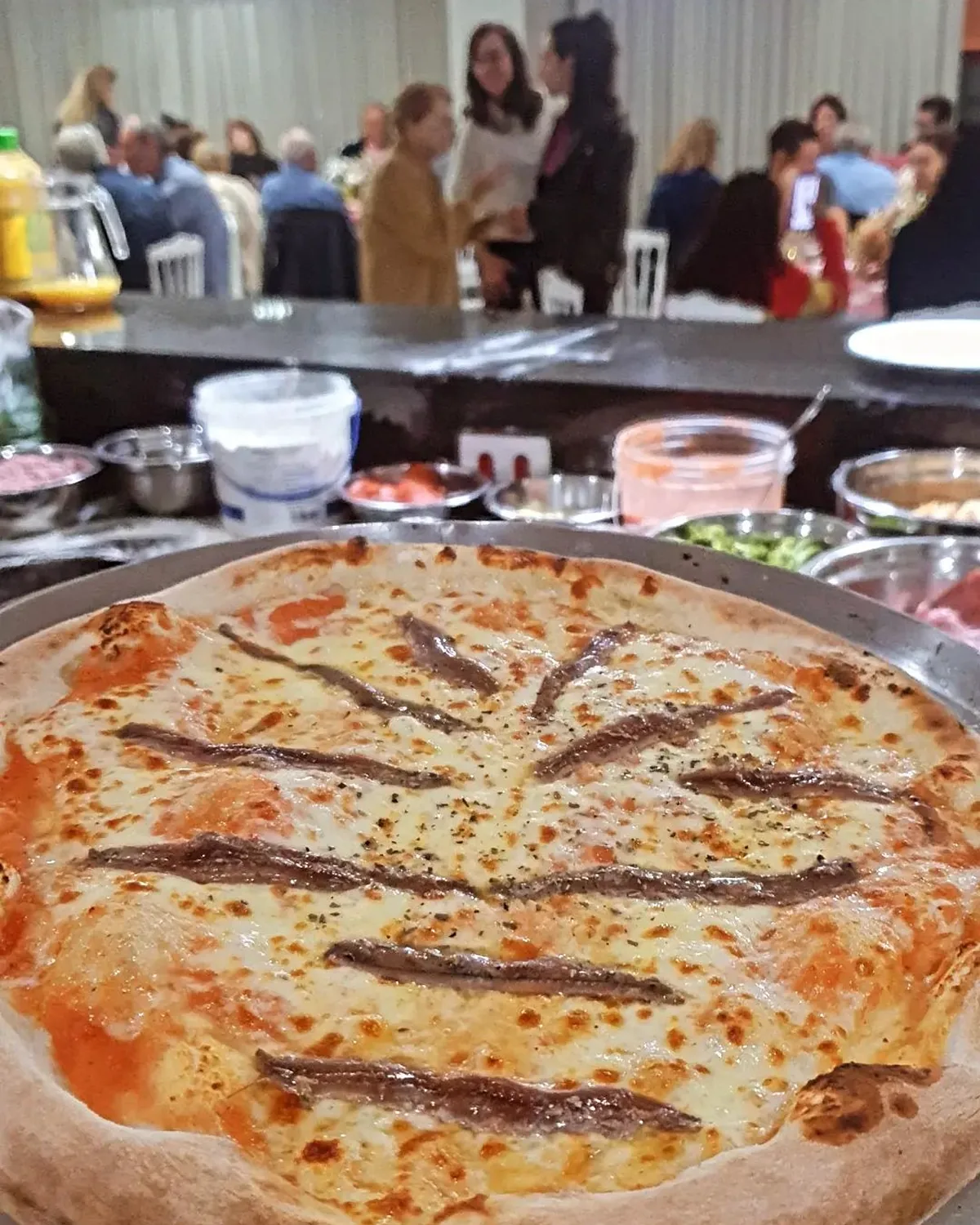 Mesa de evento com diversas pizzas artesanais servidas ao ar livre